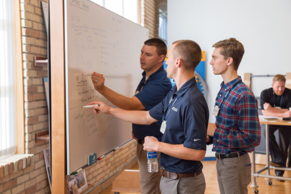 Engineers working on a problem around a whiteboard