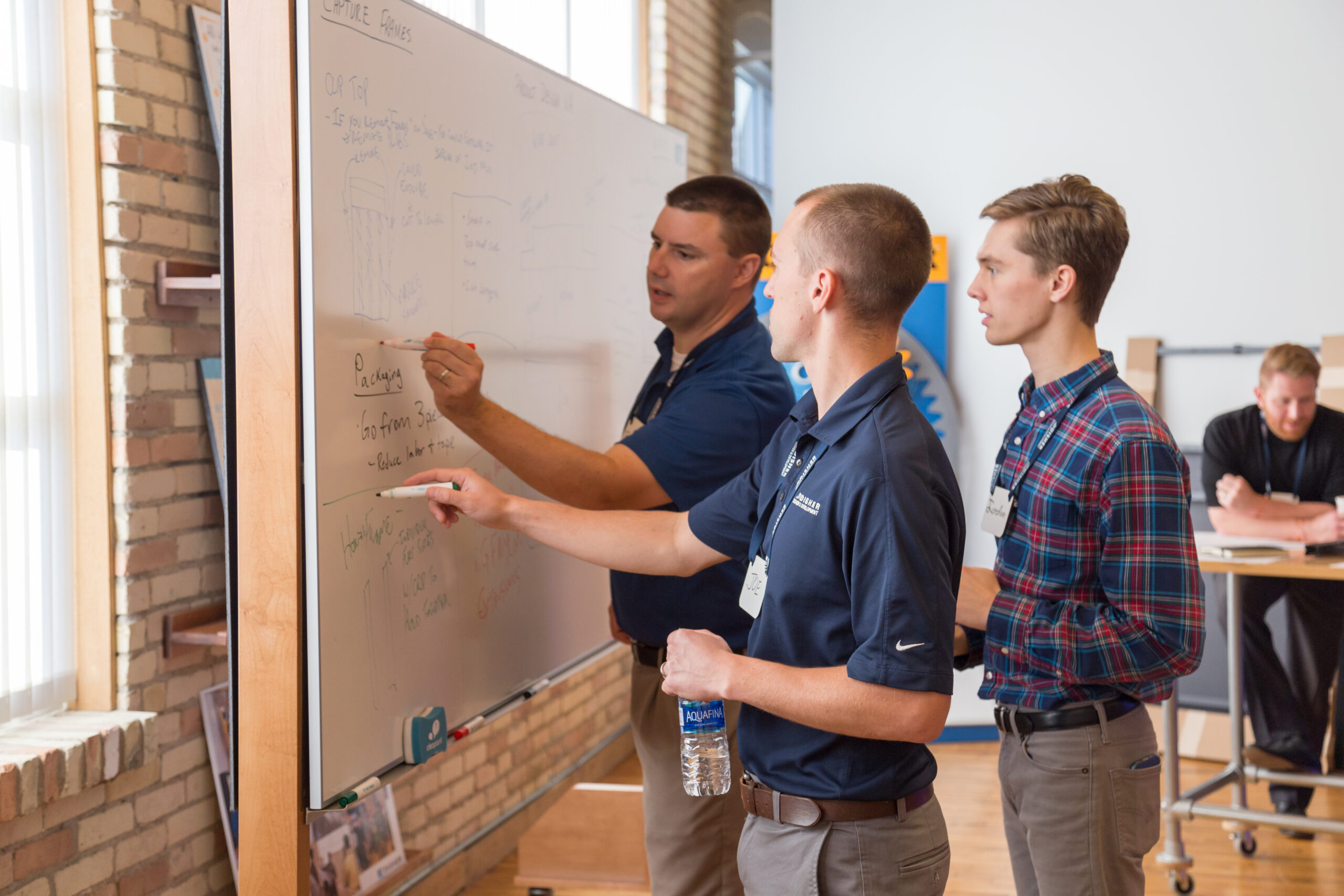Engineers working on a problem around a whiteboard